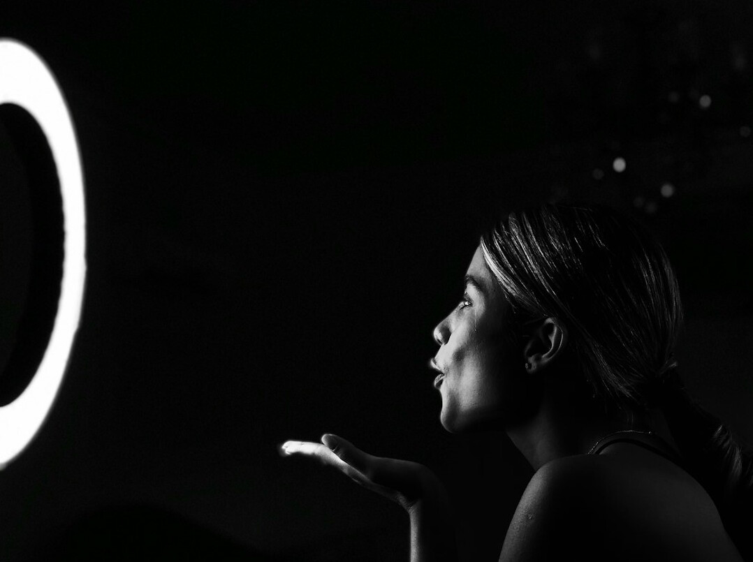 Young woman filming vertical video with smartphone and ring light