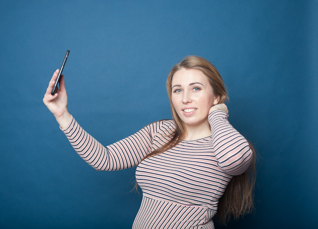 Young woman recording a story with a smartphone on a selfie stick